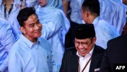 Cawapres Gibran Rakabuming Raka (kiri) dan Cawapres Muhaimin Iskandar tertawa saat menghadiri debat pertama di kantor Komisi Pemilihan Umum (KPU) di Jakarta Selasa malam, 12 Desember 2023.