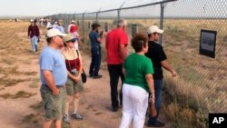 FILE - Visitors at the Trinity site, where the first atomic bomb was tested in 1945, look at historic photographs from the project at White Sands Missile Range, N.M., July 16, 2005. 