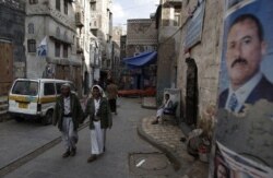 FILE - People walk along a street in the old city of Sanaa, Yemen, Aug. 7, 2011