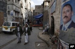 FILE - People walk along a street in the old city of Sanaa, Yemen, Aug. 7, 2011