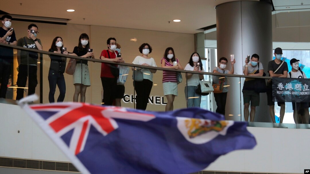 Protesters sing "Glory to Hong Kong" and wave a Hong Kong colonial flag in a shopping mall during a protest against China's national security legislation for the city, in Hong Kong, Friday, May 29, 2020.