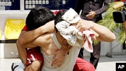 A North Korean man offers a piggy ride to his sick compatriot as they are led from a police cell to an interrogation room at a police station in Pathum Thani province, north of Bangkok. (File)