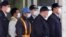 A masked man, third from left with blue cap, believed to be former Nissan Chairman Carlos Ghosn, walks out with security guards from Tokyo Detention Center in Tokyo, March 6, 2019, after posting 1 billion yen ($8.9 million) in bail.