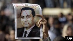 Демонстрант держит перчеркнутую фотографию президента Хосни Мубарака