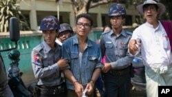 Police officers accompany Nyi Nyi Lwin, second from left, also known as Shin Gambira, a former Buddhist monk and a leader of the 2007- Saffron Revolution, to a courthouse in Mandalay, Myanmar, Feb. 16, 2016.