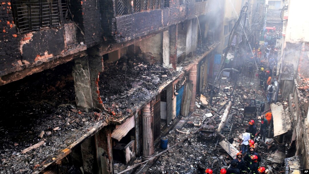 Penduduk setempat dan petugas pemadam kebakaran berkumpul di sekitar bangunan yang hangus akibat kebakaran di Dhaka, Bangladesh, 21 Februari 2019.