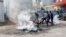 FILE - Police officers extinguish fire burning tyres after dispersing a protest near the United Nations' MONUSCO mission headquarters in downtown Kinshasa, Democratic Republic of Congo, February 12, 2024.