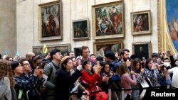 Visitantes del Museo del Louvre, en París, toman fotos de la Mona Lisa de Leonardo Da Vinci, el 3 de diciembre de 2018.