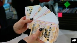 FILE - A lottery representative hands out free Powerball tickets at Russ's Market in Lincoln, Neb.