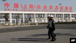 FILE - Security guards patrol the main gate of the China (Shanghai) Pilot Free Trade Zone at the Pudong International Airport in Shanghai, China.