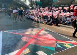 FILE - A image that has an X mark on the face of Commander in chief Senior Gen. Min Aung Hlaing is seen on a road as anti-coup protesters gather outside the Hledan Centre in Yangon, Myanmar, Feb. 14, 2021.