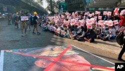 A large image that has an X mark on the face of Commander in chief Senior Gen. Min Aung Hlaing, also chairman of the State Administrative Council, lies on a road as anti-coup protesters gather outside the Hledan Centre in Yangon, Myanmar, Feb. 14, 2021.
