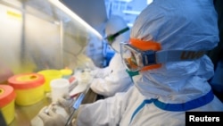 Workers in protective suits conduct RNA tests on specimens inside a laboratory at a center for disease control and prevention, as the country is hit by an outbreak of the novel coronavirus, in Taiyuan, Shanxi province, China, Feb. 14, 2020.