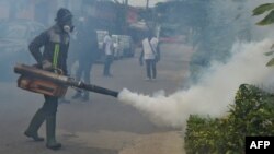 FILE - Officers of the National Institute for Public Hygiene (INHP) fumigate an area to prevent mosquitos from breeding as part of a campaign against mosquito-borne viruses, in Abidjan, June 3, 2019.