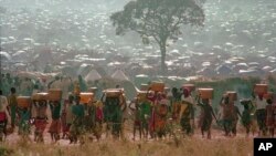FILE - Refugees who fled the genocide in Rwanda carry water containers back to their huts at a refugee camp in Tanzania on May 17, 1994. French President Emmanuel Macron reportedly will say on April 7, 2024, that the genocide could have been stopped by France and its allies.
