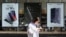 FILE - A woman checks her phone as she walks by posters adverting smartphones at a mobile phone store in Seoul, South Korea, Oct. 17, 2017.
