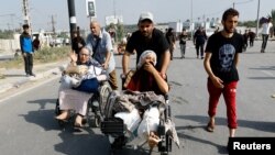 FILE - An injured Palestinian woman, was staying at Al Shifa hospital, flees north Gaza as Israeli tanks roll deeper into the enclave, amid the ongoing conflict between Israel and Hamas, in the central Gaza Strip November 10, 2023.