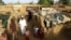 FILE - An internally displaced Sudanese family poses for a photograph outside their makeshift shelter within the Kalma camp for internally displaced persons (IDPs) in Darfur.