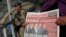 Under the watchful eye of a Turkish army soldier standing guard outside a court, a protester holds a copy of the Cumhuriyet newspaper, with headline in Turkish reading: 'We want justice," during a demonstration against the trial of journalists and staff from the newspaper, accused of aiding terror organizations, in Silivri, Turkey, Sept. 11, 2017.
