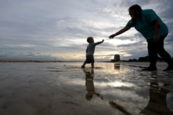 Nikita Pero de Gulfport, Mississippi, camina con su hijo Vinny Pero, de 2 años, en la playa a lo largo del Golfo de México en Biloxi, Mississippi., el lunes 14 de septiembre de 2020.