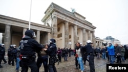Demonstrators are detained by police officers during a protest against the government's coronavirus disease (COVID-19) restrictions, next to the Brandenburger Gate in Berlin, Nov. 18, 2020.
