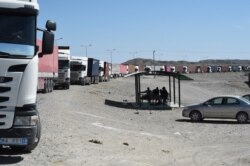 Truck drivers sit on a shelter beside trucks parked alongside a road near the closed Pakistan-Iran border in Taftan on Feb. 25, 2020, as fears over the spread of the COVID-19 coronavirus escalate.