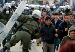 Riot police scuffle with migrants during a protest in Mytilene port on the northeastern Aegean island of Lesbos, Greece, on Feb. 4, 2020.