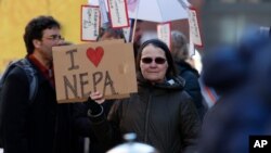 FILE - Joan Lutz of Boulder, Colo., waves a placard at a rally of advocates to voice opposition to efforts by the Trump administration to weaken the National Environmental Policy Act, Feb. 11, 2020, in Denver.