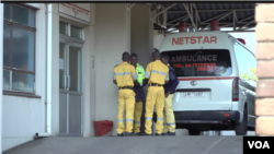 Employees block the media as Dr. Peter Magombeyi, of the Zimbabwe Hospital Doctors Association, is transported to the airport to fly to South Africa for what his medical team calls "urgent" treatment, in Harare, Sept. 26, 2019. (C. Mavhunga/VOA)