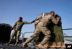 Members of the U.S. Air Force load containers of humanitarian aid onto a plane at Al Udeid Air Base in Qatar before dropping them over the Gaza Strip on March 29, 2024.