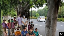 Former diplomat Virendra Gupta and his singer wife Veena Gupta with underprivileged children whom they teach on a sidewalk in New Delhi, India, Sept. 3, 2020. They say the goal is to keep them learning and not left behind when schools reopen.