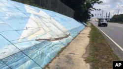 FILE - Traffic passes a mural of the slave ship Clotilda along Africatown Blvd. in Mobile, Alabama, May 30, 2019.