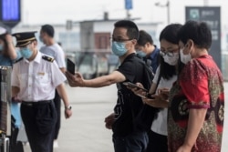 FILE - A man wears a face mask as he scans a code before entering the Wuhan Railway Station, in China's central Hubei province on May 28, 2020.