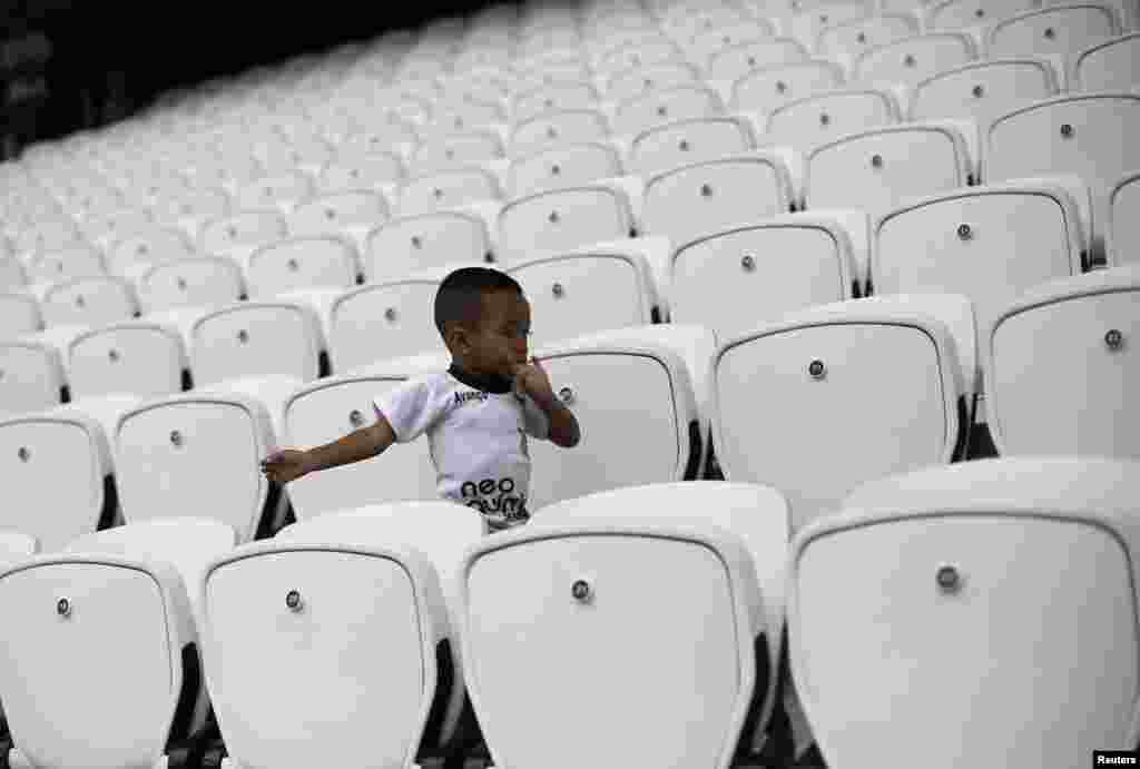 Relative of an employee runs between the bleachers before workers play in a soccer match to commemorate Labour Day at the Arena Sao Paulo Stadium in Brazil, May 1, 2014.