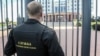 FILE - A guard stands behind a fence at the main entrance of the Moscow Regional Court, in Moscow, Russia, Aug. 1, 2017.