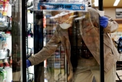 FILE - A shopper wears a mask and gloves to protect against coronavirus as he shops at a grocery store in Mount Prospect, Illinois, May 13, 2020.