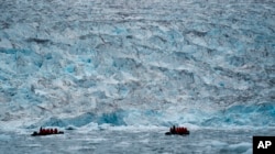 FILE - Two groups from the Poseidon Expeditions tour company look at a glacier in the Scoresby Sund, Sept. 7, 2023, in Greenland.