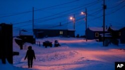 FILE - A woman walks before dawn in Toksook Bay, Alaska, a mostly Yuip'ik village, Jan. 20, 2020. The U.S. Supreme Court will hear arguments April 19, 2021, in a case that will decide who is eligible for federal virus relief set aside for tribes.