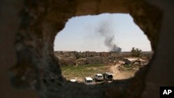 FILE - Smoke rises over Islamic State-held Baghouz, the last territory held by militants in Syria, as U.S.-backed Syrian Democratic Forces pound area with airstrikes, artillery on March 11, 2019.