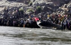 Ethiopians who fled the ongoing fighting in Tigray region prepare to cross the Setit River on the Sudan-Ethiopia border in Hamdayat village in eastern Kassala state, Sudan, Nov. 14, 2020.