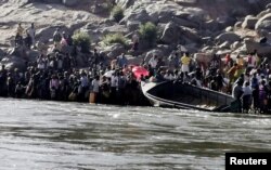 Ethiopians who fled the ongoing fighting in Tigray region prepare to cross the Setit River on the Sudan-Ethiopia border in Hamdayat village in eastern Kassala state, Sudan, Nov. 14, 2020.