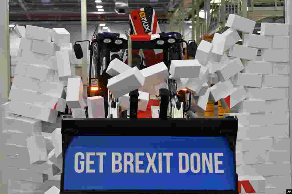 Britain&#39;s Prime Minister Boris Johnson drives a JCB through a symbolic wall with the Conservative Party slogan &#39;Get Brexit Done&#39; in the digger bucket, during an election campaign event at the JCB manufacturing facility in Uttoxeter, England.