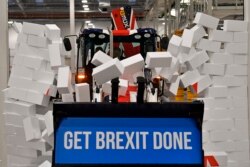 Britain's Prime Minister Boris Johnson drives a JCB through a symbolic wall with the Conservative Party slogan 'Get Brexit Done' in the digger bucket, during an election campaign event at the JCB manufacturing facility in Uttoxeter, England.