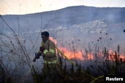 A firefighter works to put out a blaze after rockets were fired from Lebanon toward Israel, in Kiryat Shmona, Israel, on Sept. 18, 2024.