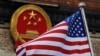 Bendera Amerika Serikat berkibar di depan lambang nasional China di luar Balai Agung China di Beijing, 9 November 2017. (Foto: Andy Wong/AP Photo)