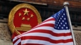 Bendera Amerika Serikat berkibar di depan lambang nasional China di luar Balai Agung China di Beijing, 9 November 2017. (Foto: Andy Wong/AP Photo)