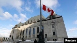 FILE - A worker raises a Canadian flag in front of the Supreme Court building in Ottawa.