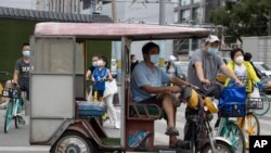 Residents wearing masks to curb the spread of the coronavirus wait at a traffic junction in Beijing on Wednesday, June 17, 2020.