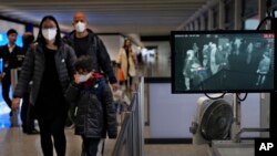 Health surveillance officer use temperature scanner to monitor passengers arriving at Hong Kong International Airport in Hong Kong, Jan. 25, 2020.