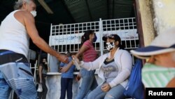 La enfermera Vanessa Castro vierte alcohol en las manos de los clientes a la entrada de un mercado público en Maracay, Venezuela, el 4 de septiembre de 2020. [Foto: Reuters]